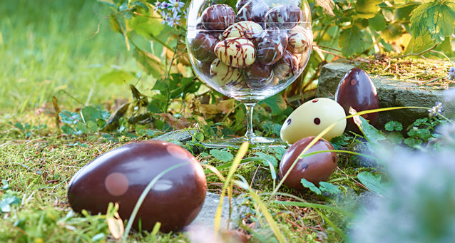 Milk, dark, and white chocolate eggs hiding in a grassy scene for Easter.