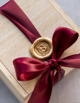 Our signature wooden box with satin ribbon and hand-stamped wax seal.