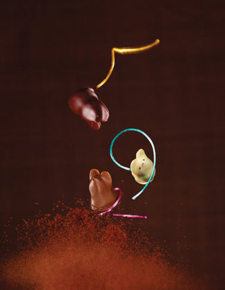 Three chocolate bonbon mice with silken colored tails falling 