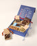 An open blue box with an assortment of gourmet chocolates (chocolate mice, Snowmen, deer and assorted shapes) and baked goods (chocolate chip cookies). The main box is navy blue the inside of the open lid depicts rows of colorful illustrations and text.