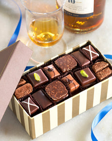 Box of assorted chocolates with a glass of whiskey and bottle in the background