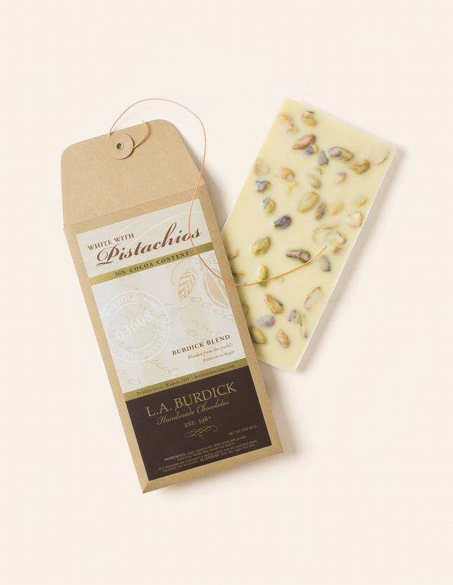 White chocolate bar studded with pistachios shown next to it's branded envelope packaging.