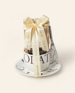 Gift set with an L.A. Burdick branded cup, saucer, and white drinking chocolate with whisk.