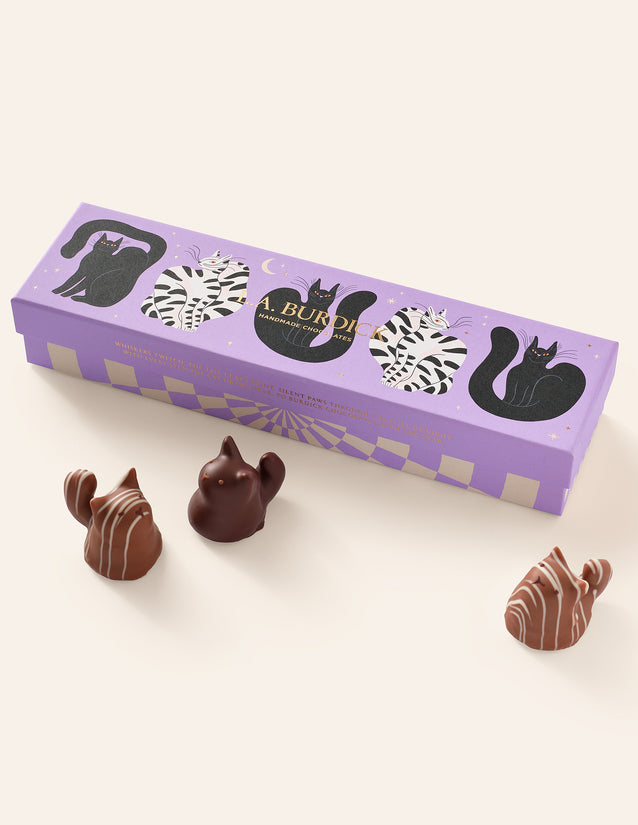 Three Chocolate Cats shown in front of their closed purple gift box, featuring whimsical cat illustrations.
