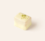 Single rectangular piece of artisan white chocolate with a smooth coating and green garnish on top, photographed on a light background.