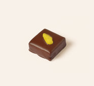 Square dark chocolate bonbon with a slice of pistachio on the top