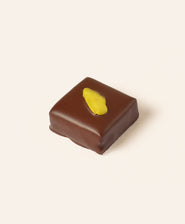 Square dark chocolate bonbon with a slice of pistachio on the top