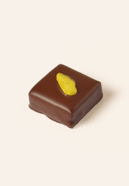 Square dark chocolate bonbon with a slice of pistachio on the top