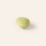 Green textured marzipan egg on a cream background