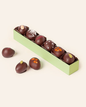Six dark chocolate–enrobed marzipan eggs with assorted garnishes in a long green gift box