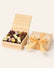 Wooden gift box tied with yellow gingham ribbon filled with chocolate bunnies, dark chocolate truffles, and marzipan eggs