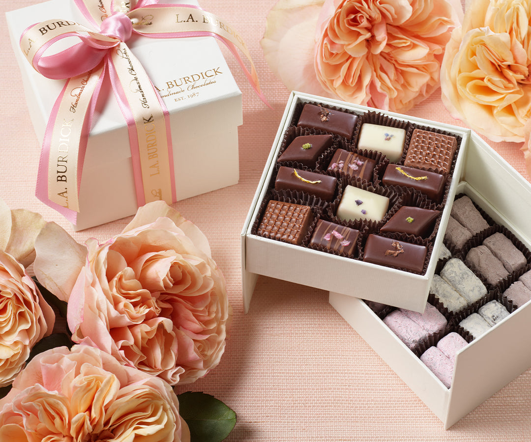 Box of chocolate bonbons surrounded by flowers