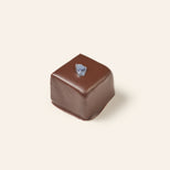 Square chocolate bonbon adorned with candied lavender on a beige background