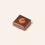 Square dark chocolate bonbon with a milk chocolate lily pad on the top surface