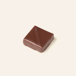 Square dark chocolate bonbon on a cream background