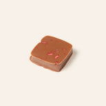 Chocolate bonbon with strawberry pieces on a light cream background