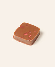 Chocolate bonbon with strawberry pieces on a light cream background