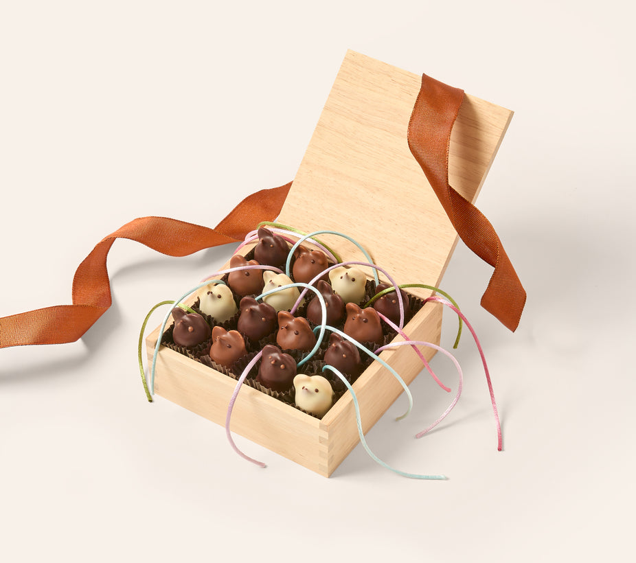 Wooden box filled with 16 dark, milk and white chocolate mice with silk tails. Tied with a pumpkin colored ribbon on a cream background.