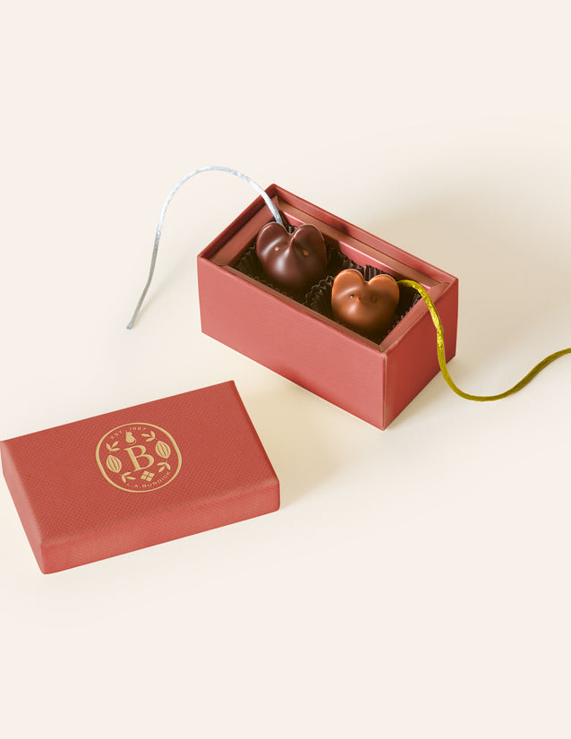 Red chocolate box with two mice bonbons with silk tails on a cream background 