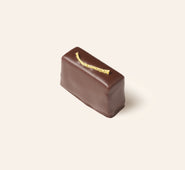 Chocolate bonbon with a lemon peel accent on a beige background