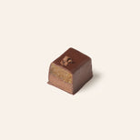 Rectangular chocolate bonbon cut in half on a cream background.