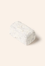 Rectangular chocolate bonbon covered in white powdered sugar on a cream background.