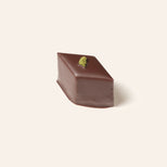 Chocolate bonbon with a green candied mint topping on a cream background