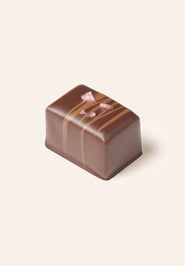 Chocolate bonbon with decorative elements on a light beige background