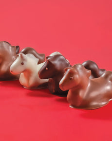 Chocolate horse figurines in various colors on a red background