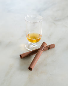 Scotch glass and two chocolate cigars on a marble background