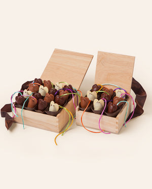 Two wooden gift boxes filled with chocolate mice on a white background